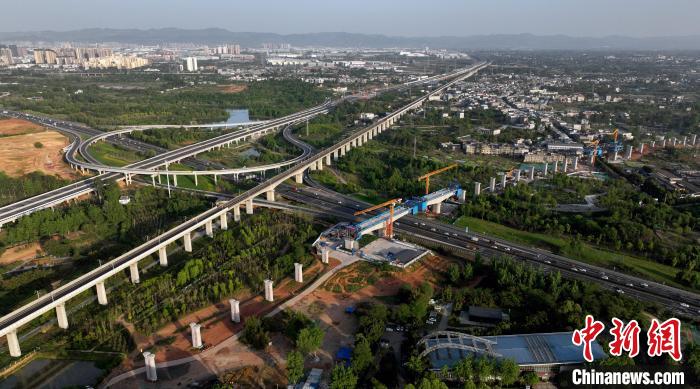 航拍正在建設的跨越成都繞城高速公路連續(xù)梁施工現(xiàn)場，旁邊依次為已運營的成渝高速鐵路和機場高速公路?！⒅铱?攝