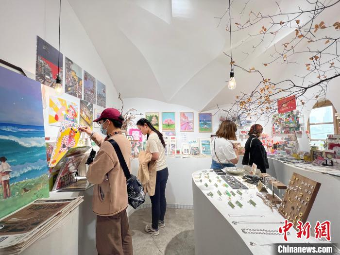 圖為藝術(shù)品商店內(nèi)，顧客挑選插畫作品?！＄婌?攝