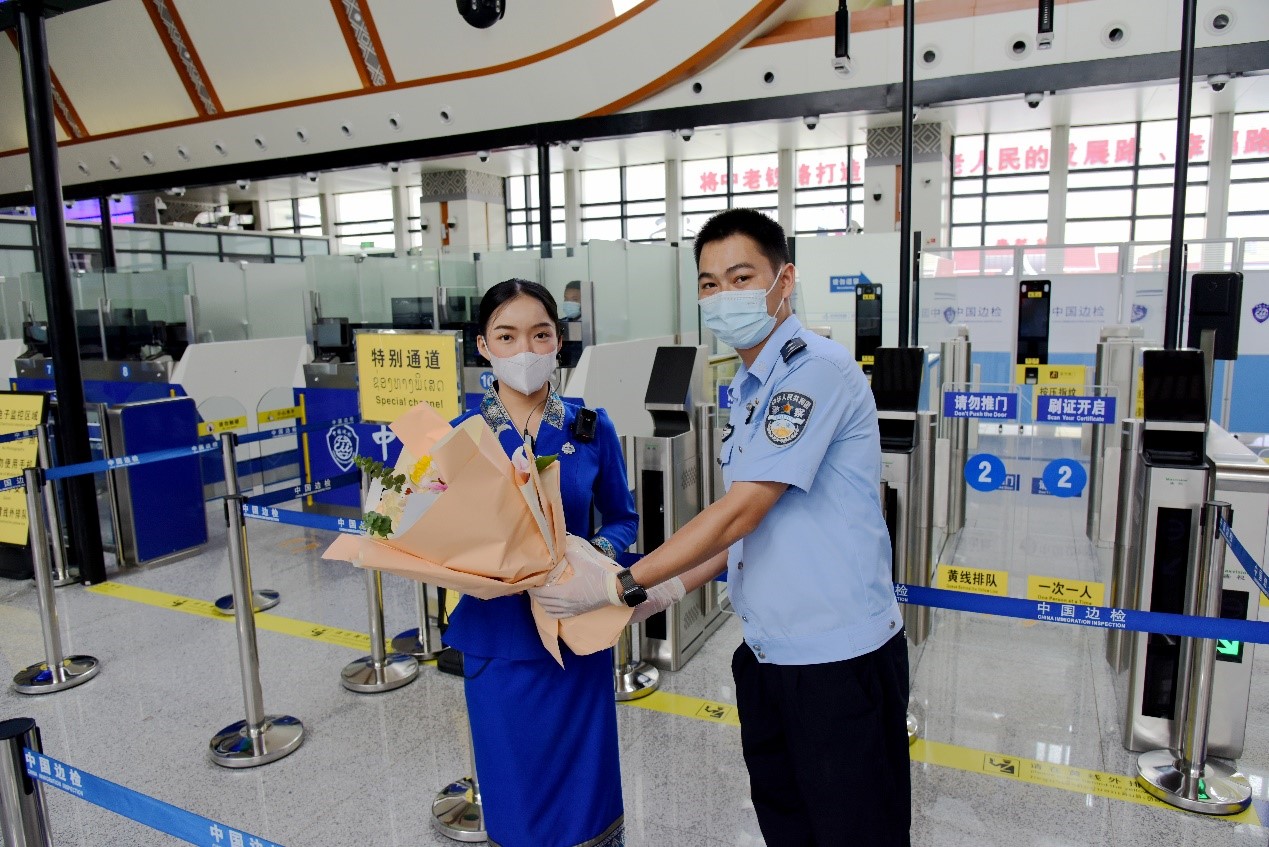 磨憨出入境邊防檢查站民警為中老鐵路第100萬名出入境旅客，D888次國際旅客列車老撾籍乘務(wù)員森達拉·妮緹婭（Sengdala Nitiya），送上鮮花。黃遠飛 攝