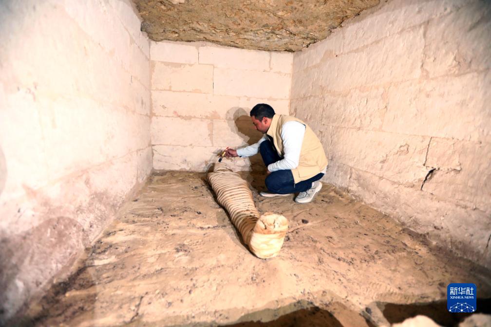 10月15日，在埃及明亞省考古現(xiàn)場，考古人員清理一座石鑿墓中的木乃伊。新華社發(fā)（艾哈邁德·戈馬攝）