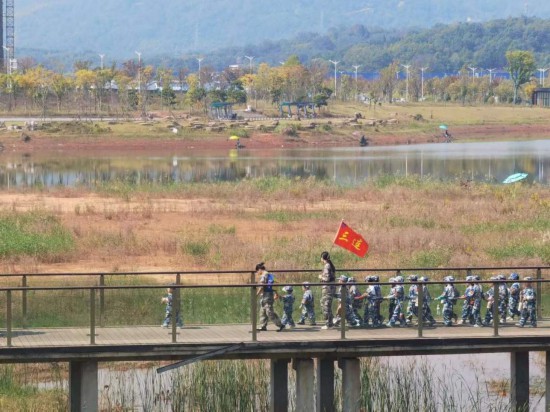 　　10月24日，秋游的幼兒園小朋友在老師帶領下走在清水塘公園里的木橋上。本報記者 常雯宜攝