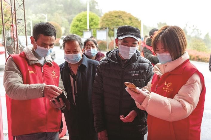 長(zhǎng)沙縣黨員志愿者正在幫助參與核酸檢測(cè)的群眾掃描“場(chǎng)所碼”。劉思源 攝