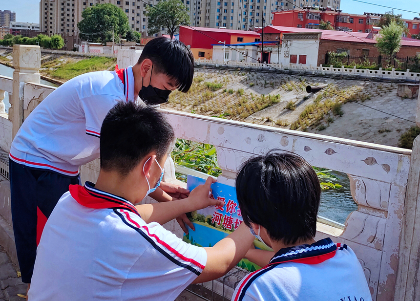 徐水小學(xué)學(xué)雷鋒志愿者在瀑河河邊張貼防溺水警示標(biāo)語。 徐水區(qū)委宣傳部供圖