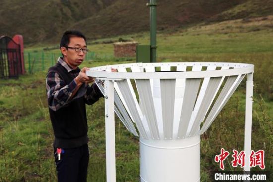 圖為班瑪縣氣象局工作人員在維護(hù)藏雪茶基地氣候站。青海省氣象局供圖