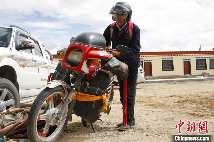 圖為白瑪準(zhǔn)備騎摩托車巡湖?！≮w朗 攝