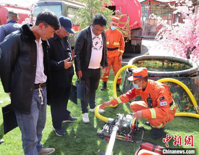 圖為森林消防員為護(hù)林員講解滅火裝備的使用方法?！〔际猩窒乐ш?duì) 供圖