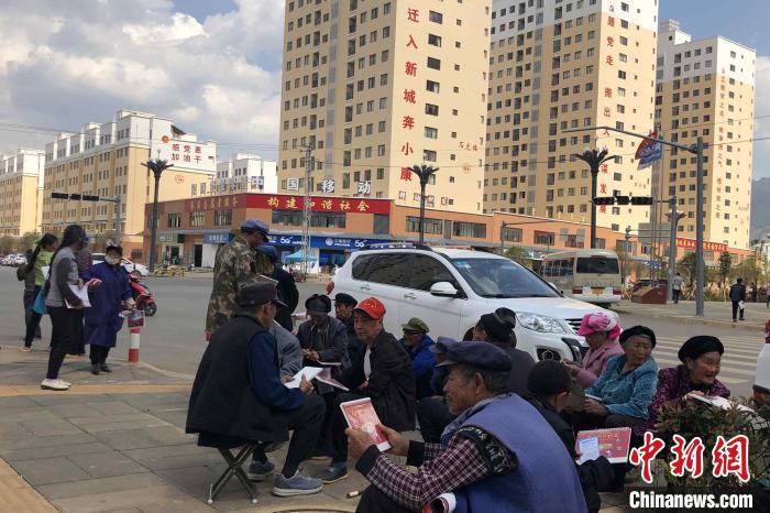 圖為會(huì)澤縣城易地扶貧搬遷安置點(diǎn)內(nèi)，老人們聚在廣場上聊天，身后是他們的新家。　繆超 攝