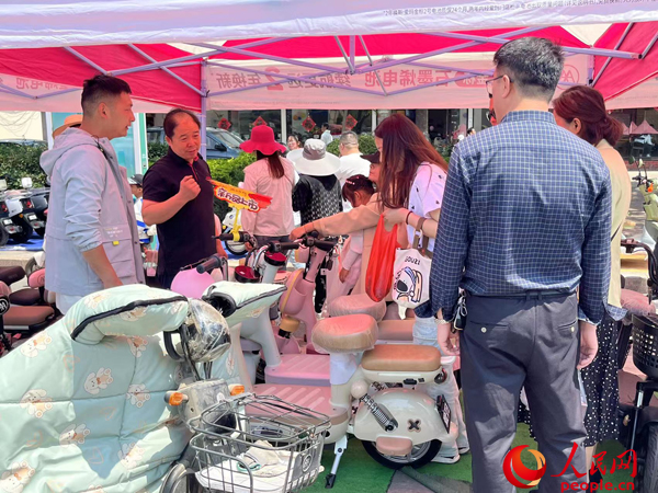 某電動自行車品牌工作人員向消費(fèi)者介紹以舊換新相關(guān)情況。人民網(wǎng)記者 杜燕飛攝