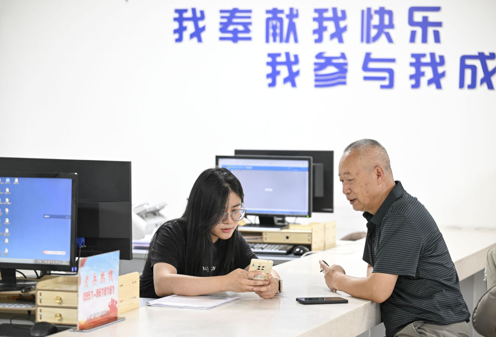 2024年6月20日，在寧夏銀川市金鳳區(qū)長城花園社區(qū)黨群服務(wù)中心，工作人員幫助居民辦理業(yè)務(wù)。圖片來源 新華社