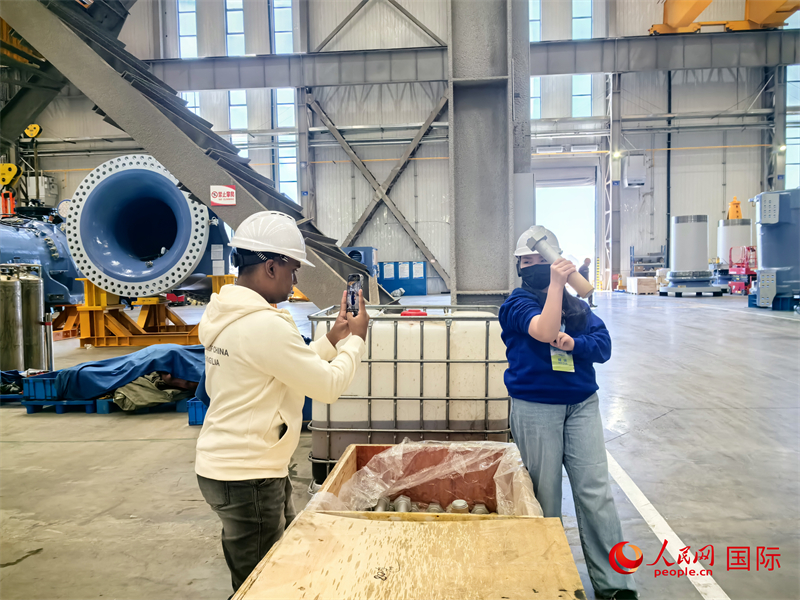 外媒記者掂量廠房內(nèi)的巨型螺栓。人民網(wǎng) 楊春燕攝