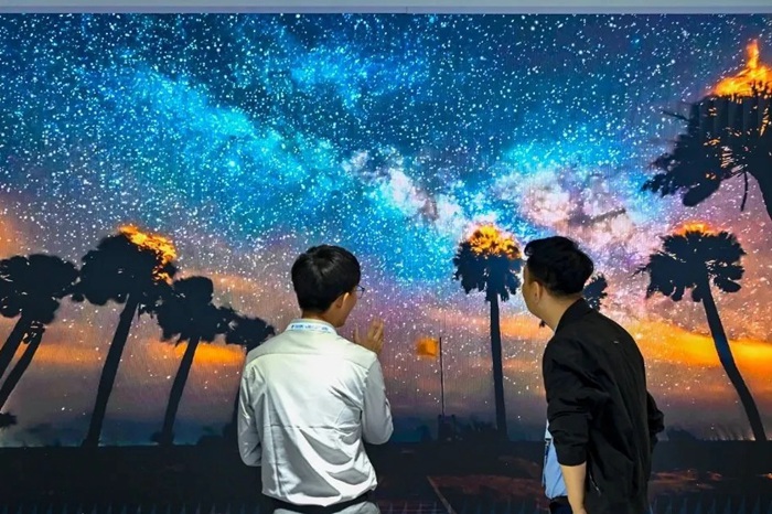 長春光博會希達(dá)電子展區(qū)，一位工作人員正在給一位觀眾講解。（長春新區(qū)供圖）