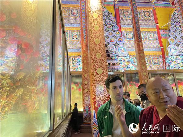 7月25日，省級非物質(zhì)文化遺產(chǎn)項目塔爾寺酥油花的代表性傳承人朋措堅參（右）在塔爾寺酥油花館講解酥油花的制作過程。人民網(wǎng) 謝瑩攝