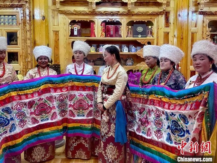 圖為女性展示村民自發(fā)繡制的“百米五彩哈達(dá)”?！±钣穹?攝