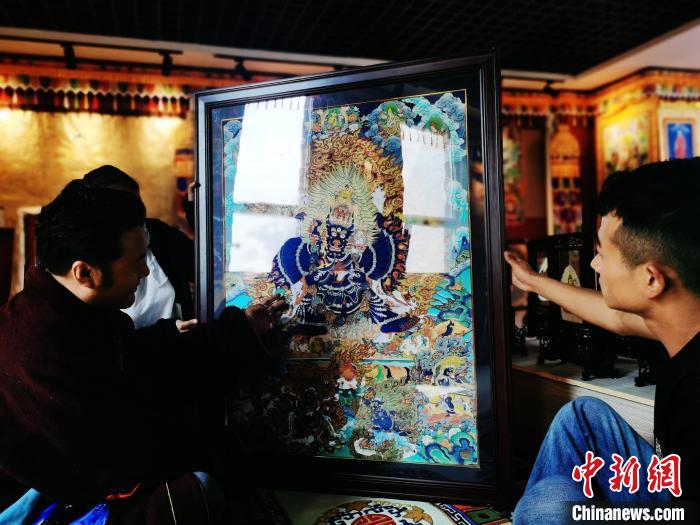 圖為久美尖措(左)與徒弟們展示唐卡作品?！?zhí)砀?攝