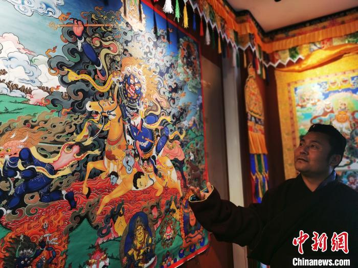 圖為久美尖措展示唐卡作品?！?zhí)砀?攝