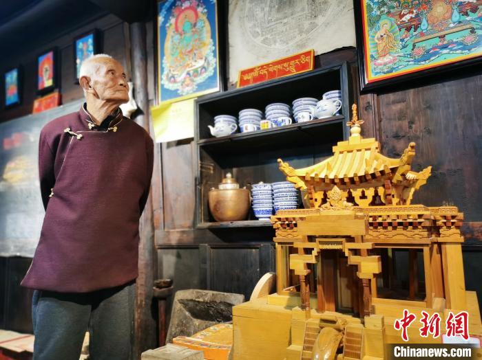 圖為古堡內(nèi)的藝人桑杰展示自己的雕刻作品?！?zhí)砀?攝