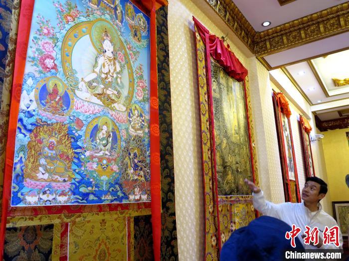 圖為完德尖措展示熱貢龍樹(shù)畫(huà)苑內(nèi)的唐卡?！?zhí)砀?攝