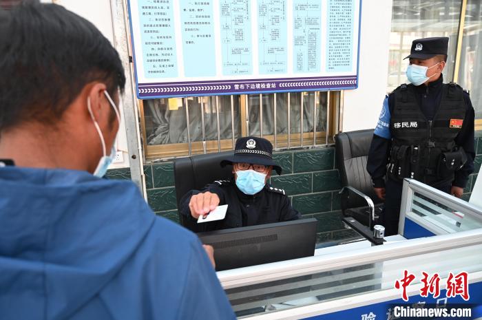 圖為移民管理警察登記完身份信息后將證件歸還給行人?！≮w朗 攝