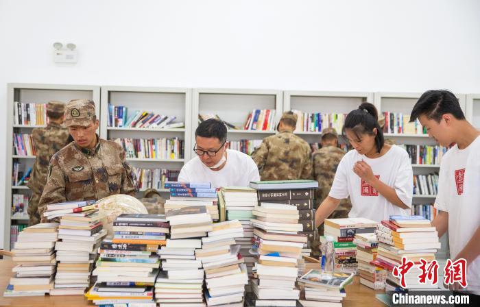 圖為志愿者們和邊防戰(zhàn)士整理圖書(shū)?！詵| 攝