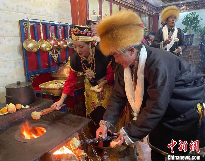 圖為人們在火上烤節(jié)日美食“結(jié)達(dá)”?！∪轿木?攝