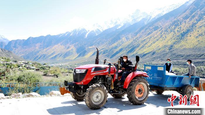 圖為工作人員將把加工完成的糌粑運(yùn)送至村民手中?！〖卫杩h融媒體中心供圖