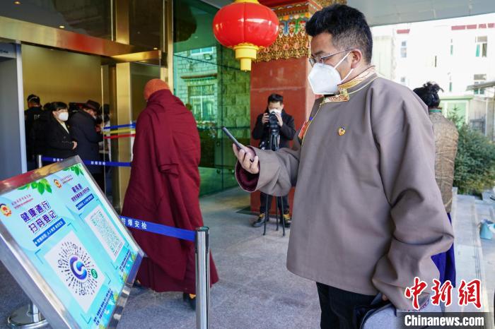 圖為政協(xié)委員掃場所碼進(jìn)入會場?！〗w波 攝