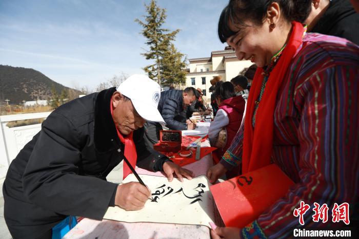 圖為林芝市文聯(lián)書法家協(xié)會(huì)會(huì)員向民眾贈(zèng)送藏文書法作品。　張力 攝