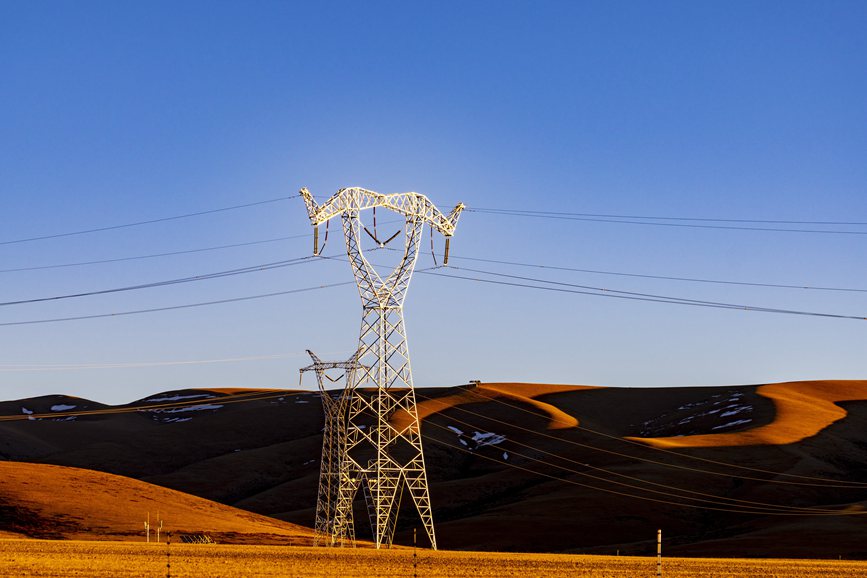 阿里地區(qū)的曠野上，電力鐵塔在夕陽(yáng)下熠熠生輝。