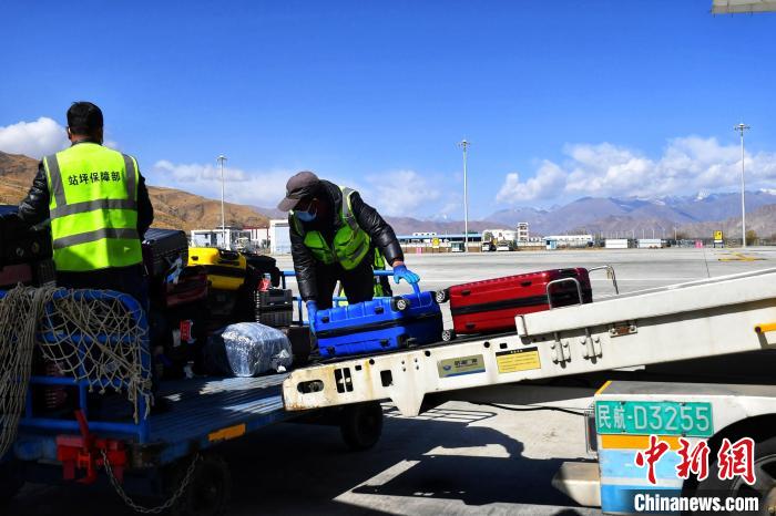圖為機(jī)場工作人員傳送旅客行李箱。　周航 攝