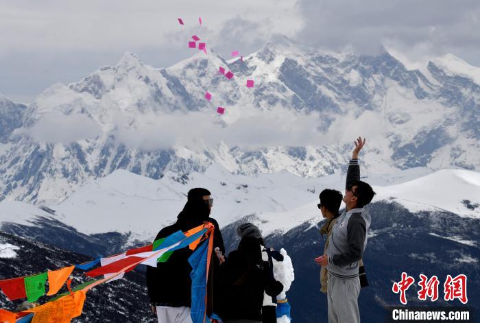 圖為5月14日，游客在西藏林芝色季拉山觀景臺拋灑“隆達”(風馬旗，藏族民眾的一種祈福方式)?！±盍?攝