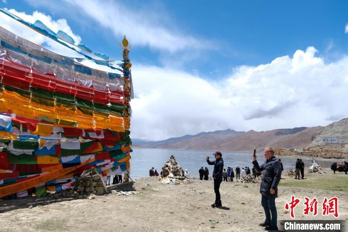 進藏參訪嘉賓在羊湖畔拍攝經(jīng)幡。　江飛波 攝